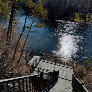 Black aluminum stairs leading down a wooded slope to the water, Lake Michigan aluminum stair builders