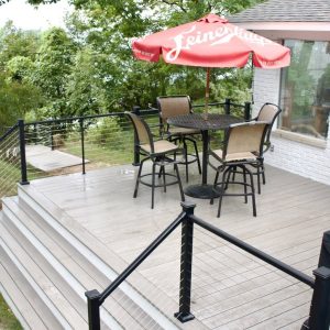 Composite deck with black aluminum railing and outdoor dining set, West Michigan composite deck builders