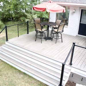 Composite deck and stairs with cable railing and patio umbrella, West Michigan composite deck builders