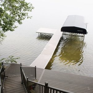 Dock and boat lift on an inland lake with aluminum stairs to the shore, West Michigan dock builders