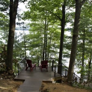 Composite lakeside deck with Adirondack chairs among the trees, Lake Michigan composite deck builders