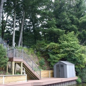 Seawall with stairs and a storage shed on a wooded lakefront lot, West Michigan seawall builders